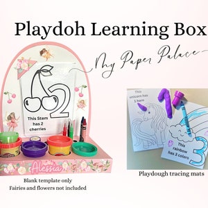 Könnte beinhalten: Rosa Holz-Play-Doh-Lernbox mit einem klaren Rahmen, Play-Doh-Behältern und Markern. Der Rahmen enthält ein Bild eines Kirschstiels mit zwei Kirschen und dem Text "This Stem has 2 cherries". Die Box enthält auch den Text "Alessia" und "Blank template only Fairies and flowers not included". Das Bild zeigt auch zwei Play-Doh-Malvorlagen mit einem Einhorn und einem Regenbogen. Die Einhorn-Vorlage hat den Text "This unicorn has 1 horn" und die Regenbogen-Vorlage hat den Text "This rainbow has 3 colours".