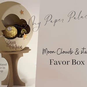Könnte beinhalten: Eine braune Pappbox in Mondform mit einer ausgeschnittenen Wolke und Sternen. Die Box steht auf einem Ständer und trägt die Aufschrift "Over the Moon". Der Text "My Paper Palace - Moon Clouds & stars Favor Box" ist im Hintergrund sichtbar.