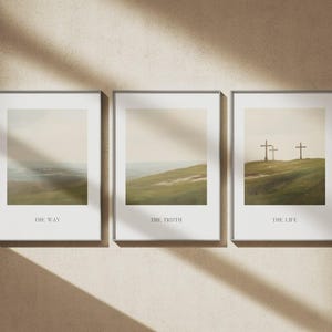 May include: Three framed art prints with landscape scenes. The prints are in silver frames and feature soft, muted colors. The first print says "THE WAY", the second says "THE TRUTH", and the third says "THE LIFE". The art prints are displayed on a beige wall.