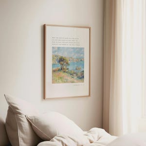 Op de afbeelding: Een ingelijste print met een landschapsschilderij van een boom, water en een lichtblauwe lucht. De print zit in een lichtbruine houten lijst. Tekst in een schreefletter staat boven de schildering.