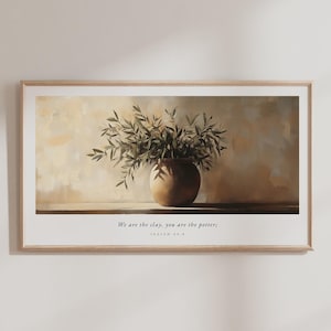 May include: A framed art print featuring a still life composition. A brown ceramic vase holds a lush arrangement of green leafy branches. The background has a neutral color palette with the text "We are the clay, you are the potter;" and "ISAIAH 64:8".