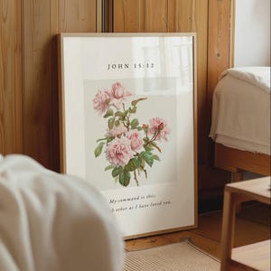 Könnte beinhalten: Ein gerahmter vertikaler Wandkunstdruck mit einer botanischen Illustration von rosa Rosen mit grünen Blättern. Der Text JOHN 15:12 steht oben und der Text My command is this: Love each other as I have loved you steht unten.