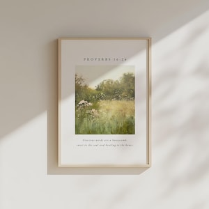 Könnte beinhalten: Gerahmter Kunstdruck mit einer Landschaftsdarstellung mit Wildblumen und Bäumen. Der Druck enthält den Text "PROVERBS 16:24" und ein Zitat. Der Rahmen hat eine helle Holzfarbe.