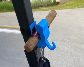 May include: A blue golf cart accessory with a hook and a cigar holder. A black towel is hanging from the hook.