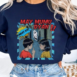 May include: Navy blue sweatshirt with a graphic print of two children looking at a ghost in a hallway. The text on the graphic says "May Mumu Dyan! Ingat Ka!"
