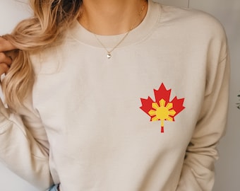 Peut inclure: Un sweat-shirt beige court avec un motif de feuille d'érable rouge arborant les couleurs du drapeau philippin. Le sweat-shirt est porté par une personne aux cheveux longs blonds et un jean bleu. Le mot "SAND" est visible dans le coin inférieur gauche de l'image.