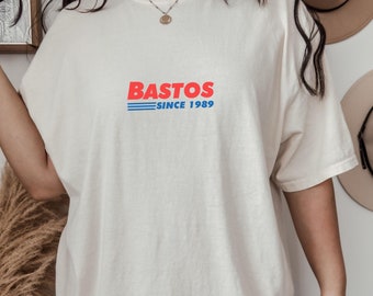 May include: A white oversized t-shirt with the text "Bastos Since 1989" in red and blue lettering.