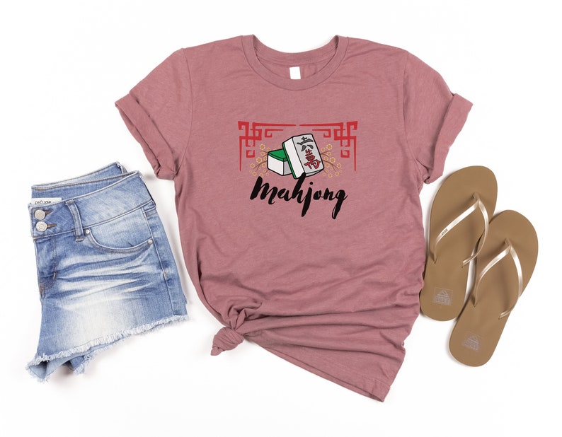 May include: A heather pink t-shirt with a graphic of mahjong tiles and the word "Mahjong" in black text.