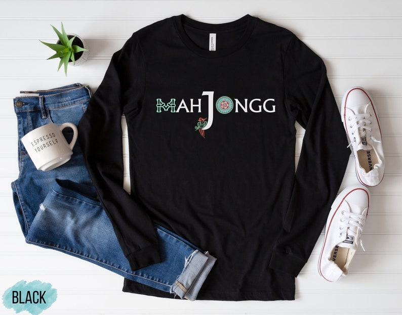 May include: Black long-sleeved shirt with the text "Mahjongg" in green, red and white. The text is stylised with a green four-leaf clover, a red circle and a white letter J.