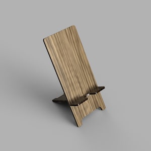 May include: A wooden phone stand with a natural wood grain finish. The stand has a simple design with a raised platform to hold a phone.