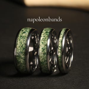 Pode incluir: Tr&ecirc;s alian&ccedil;as de prata com incrusta&ccedil;&otilde;es verdes. As alian&ccedil;as est&atilde;o empilhadas umas sobre as outras. O texto "napoleonbands" &eacute; vis&iacute;vel no fundo.