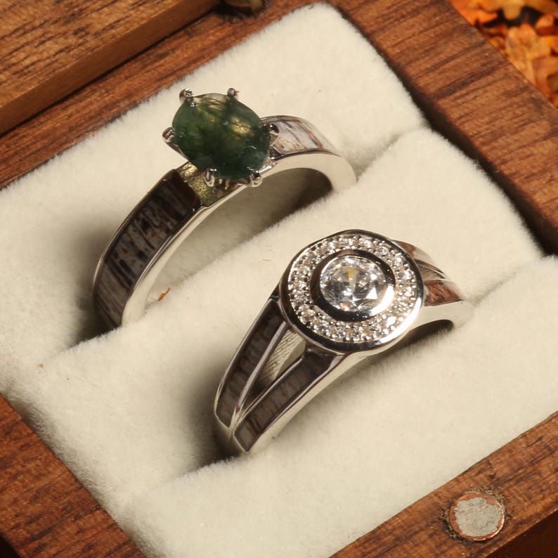 May include: Two silver rings with a green gemstone and a clear diamond in a wooden ring box.