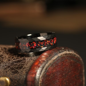 May include: A black ring with a band of red gemstones. The ring is made of a durable material and has a unique design.