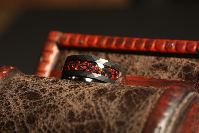 May include: A black tungsten carbide ring with a red and gold glitter inlay. The ring is in a wooden box.