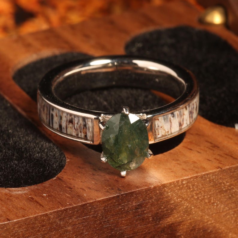 May include: A silver ring with a green gemstone set in a white antler band.