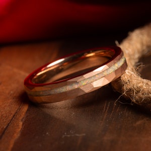 May include: A rose gold tungsten carbide ring with a white opal inlay and a hammered finish.
