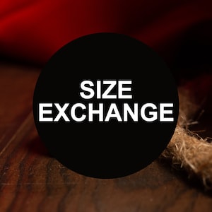 May include: A black circle with white text that reads "SIZE EXCHANGE" on a wooden surface.