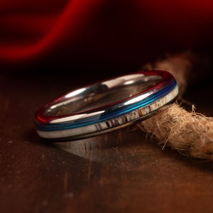 May include: A silver ring with a blue and white inlay. The inlay is made of antler and has a natural pattern. The ring is polished and has a smooth finish.