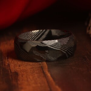 May include: A black ring with a unique patterned design. The ring is made of a durable material and has a polished finish.