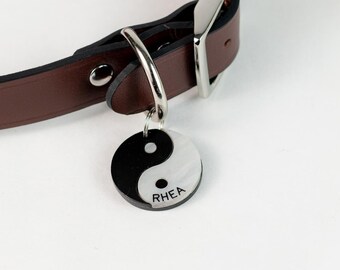 May include: Brown leather dog collar with silver bone accents and a silver and black yin yang dog tag with the name "Rhea" engraved on it.