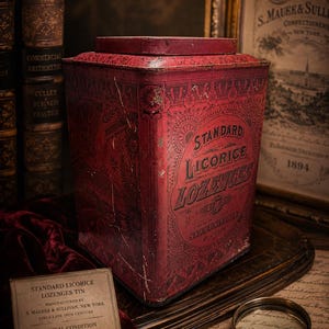 May include: A vintage red Standard Licorice Lozenges tin with ornate lettering and graphics. The tin, manufactured by S. Maurer & Sullivan, New York, is from the late 19th century. The image includes a magnifying glass and antique documents.