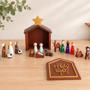 Puede incluir: Un set de nacimiento de madera con figuras tipo peg doll de la sagrada familia, los reyes magos, pastores y animales. Incluye un establo con una estrella dorada y un letrero marrón con el texto en letras doradas O Holy Night.