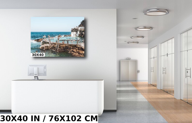 May include: A photograph of a crowded outdoor pool with people swimming and sunbathing. The pool is surrounded by rocks and a blue sky. The image is 30x40 inches.