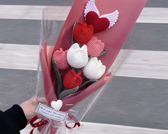 May include: A bouquet of crocheted tulips in red, white, and pink with green stems. The bouquet is wrapped in pink tissue paper and clear cellophane. A white crocheted heart with the text "Good vibes for Always!" is attached to the bouquet.