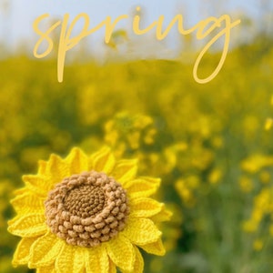 May include: A crocheted sunflower with yellow petals and a brown center, set against a blurred background of yellow flowers and the word "spring" in yellow text.