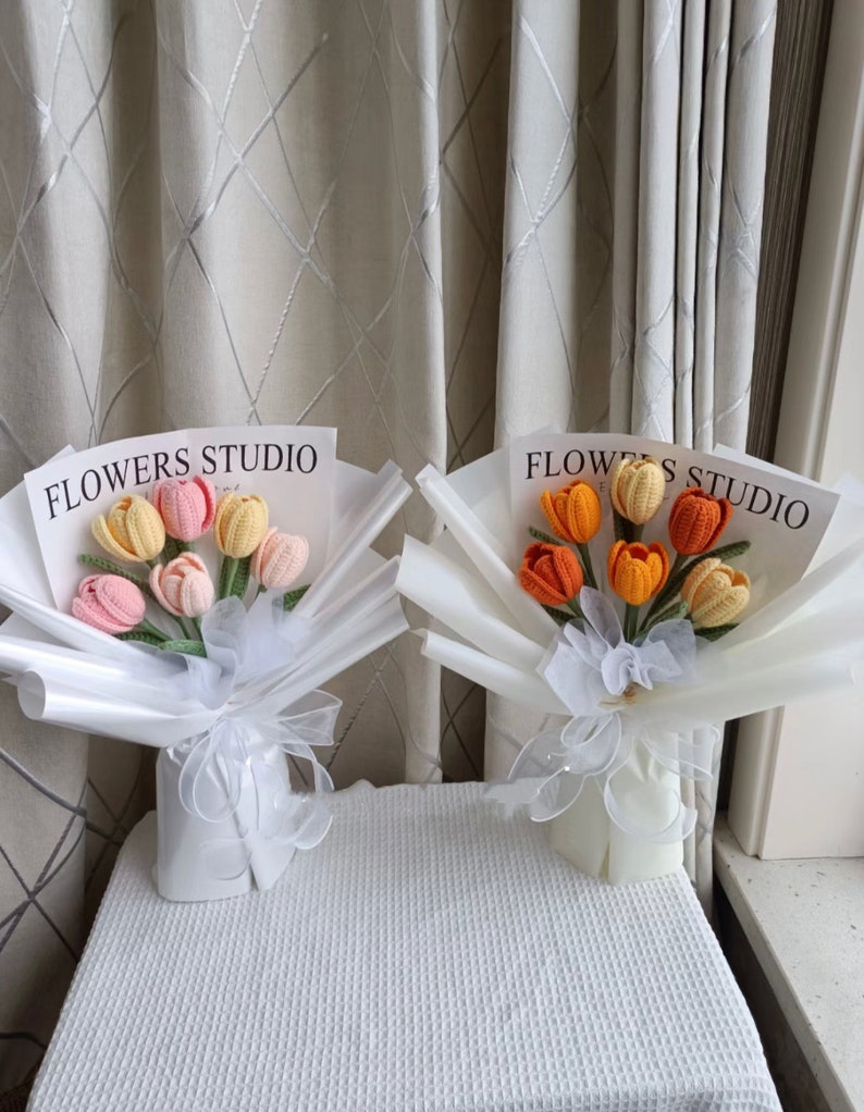 K&ouml;nnte beinhalten: Zwei Str&auml;u&szlig;e geh&auml;kelter Tulpen in wei&szlig;em Verpackungspapier. Die Str&auml;u&szlig;e sind mit "Flowers Studio" beschriftet. Ein Strau&szlig; hat rosa, orange und gelbe Tulpen. Der andere Strau&szlig; hat orange und gelbe Tulpen.