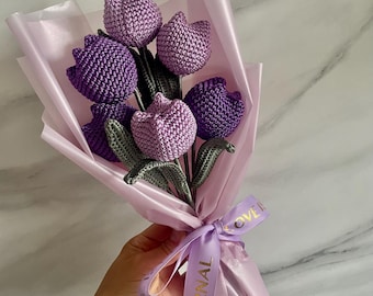May include: A bouquet of purple crocheted tulips wrapped in pink tissue paper and tied with a purple ribbon that says "Love is Eternal".