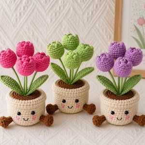 May include: Three crocheted potted plants featuring pink, green, and purple tulip flowers with green leaves. Each plant sits in a cream-coloured crocheted pot with a smiling face, pink cheeks, and two small brown feet extending from the base.