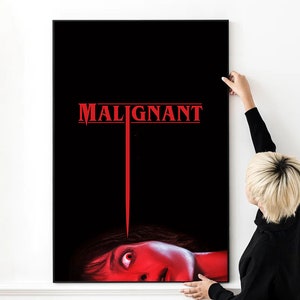Puede incluir: Un póster de película negro y rojo con el título "MALIGNANT" en letras rojas. Una línea roja se extiende desde el título hasta la cara de una mujer, que es parcialmente visible en la parte inferior del póster.