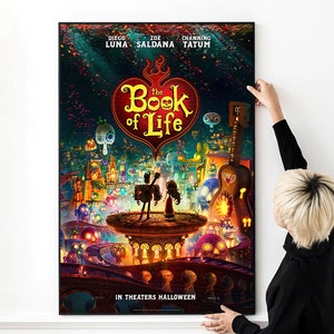 May include: Movie poster for "The Book of Life" featuring Diego Luna, Zoe Saldana, and Channing Tatum. The poster has a red heart with the title "The Book of Life" in white text. The poster is set against a colorful background with a cityscape and skeletons.