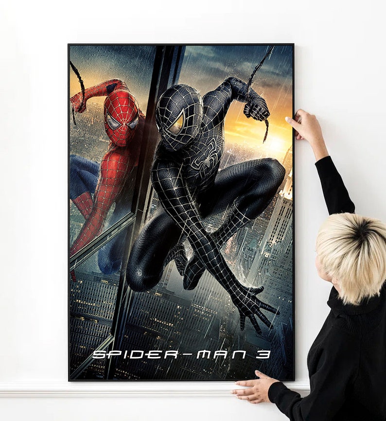 May include: A movie poster for Spider-Man 3 featuring two versions of Spider-Man, one in a red and blue suit and the other in a black suit. The poster has a dark background with a cityscape in the background.