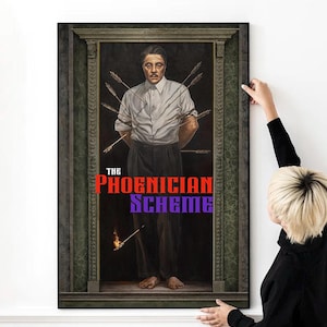 Może przedstawiać: Oprawiony wydruk przedstawiający mężczyznę przeszytego strzałami, z napisem "THE PHOENICIAN SCHEME" w kolorze czerwonym i fioletowym. Grafika przedstawia mężczyznę w białej koszuli i ciemnych spodniach, z strzałami przebijającymi jego ciało. Osoba trzyma wydruk.