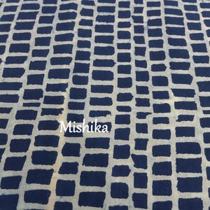 以下が含まれることがあります： 白いレンガ模様の青い布のクローズアップ。布には「Mishika」という文字が印刷されています。