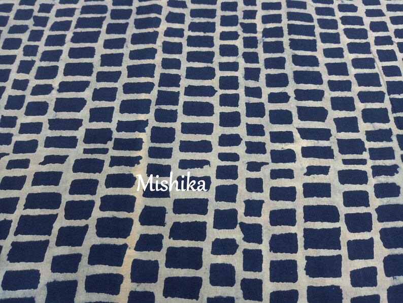 以下が含まれることがあります： 白いレンガ模様の青い布のクローズアップ。布には「Mishika」という文字が印刷されています。
