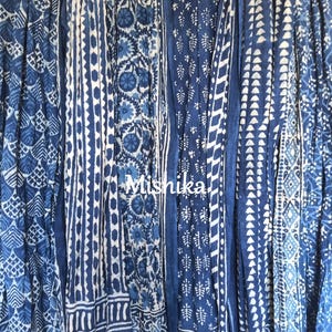 Könnte beinhalten: Eine Sammlung von sechs blauen und weißen Baumwollschals mit verschiedenen Indigo-Blockdruckmustern. Die Schals sind vertikal angeordnet und zeigen eine Vielzahl von geometrischen und floralen Mustern.