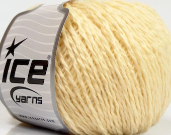May include: A round ball of pale cream-colored yarn wrapped in a paper label. The label features the black text ICE YARNS, a star icon, and the website address www.iceyarns.com printed on a light gray background with subtle wavy lines.