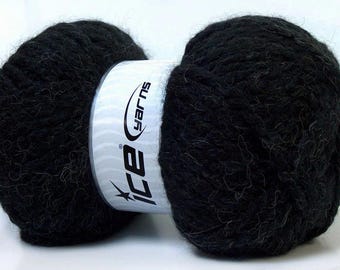 May include: A skein of black yarn with a textured, fuzzy appearance. A white paper label wraps around the center of the yarn, featuring the text Ice Yarns printed in black with a star graphic. The yarn is wound into two rounded ends.