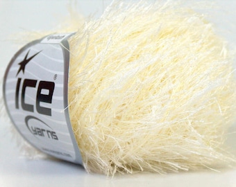 May include: A ball of cream-colored eyelash yarn with a long, fuzzy texture. A white paper label is wrapped around the side, featuring the black text ICE YARNS and a star logo. The yarn fibers are thin, shiny, and densely packed together.