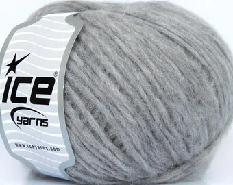 May include: A ball of light grey yarn with a fuzzy, textured appearance. A white paper label is wrapped around the side, featuring the black text "ice yarns" with a star icon and the website address "www.iceyarns.com" printed on the bottom.