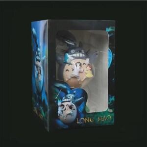 以下が含まれることがあります： 大きな灰色のトトロのフィギュアが箱に入っており、白いお腹で小さなフィギュアを持っています。箱にはフィギュアが見える窓があり、青と緑の森のシーンが描かれています。「LONG MAO」の文字が箱に印刷されています。