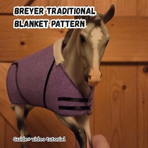 May include: A Breyer horse figurine wearing a purple blanket with black trim and buckles. The blanket has a cream-colored lining. Text on the image reads "BREYER TRADITIONAL BLANKET PATTERN" and "Guide+ video tutorial".