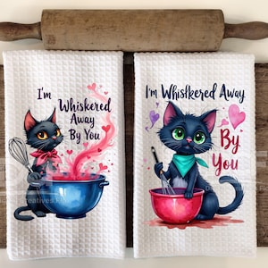 Puede incluir: Dos toallas de cocina blancas con gatos negros y corazones rojos. El texto en las toallas dice "I'm Whiskered Away By You".