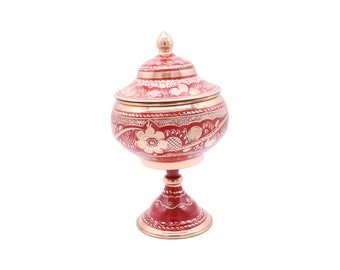 Peut inclure: Un bol décoratif rouge et or avec un couvercle et un pied. Le bol est décoré de motifs floraux complexes.