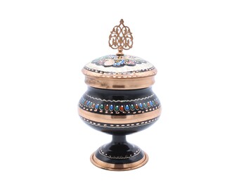 Peut inclure: Un sucrier noir et cuivre avec un couvercle décoratif et un motif floral. Le bol a une base ronde et un pied.