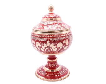 Peut inclure: Un bol décoratif rouge et or avec un couvercle et un piédestal. Le bol est décoré de motifs floraux complexes.