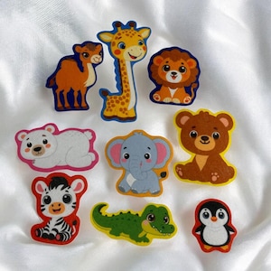 May include: A collection of colorful animal-shaped wooden cutouts, including a giraffe, lion, bear, zebra, and penguin. The cutouts are in various colors and designs, perfect for crafting or educational purposes.